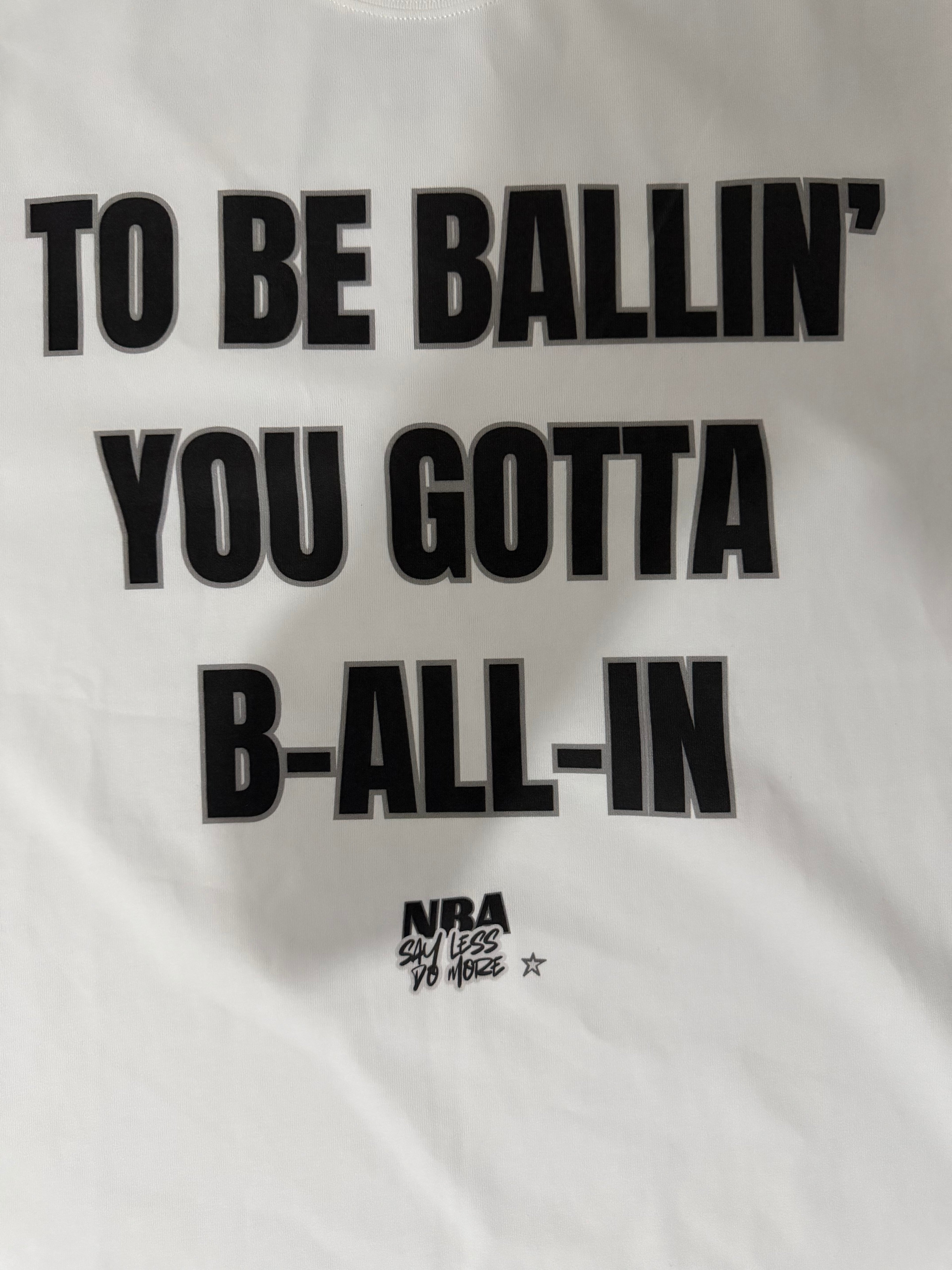 White "ALL-IN" T-shirt by NBASayLessDoMore, featuring a classic crew neck and simple design on a flat lay.